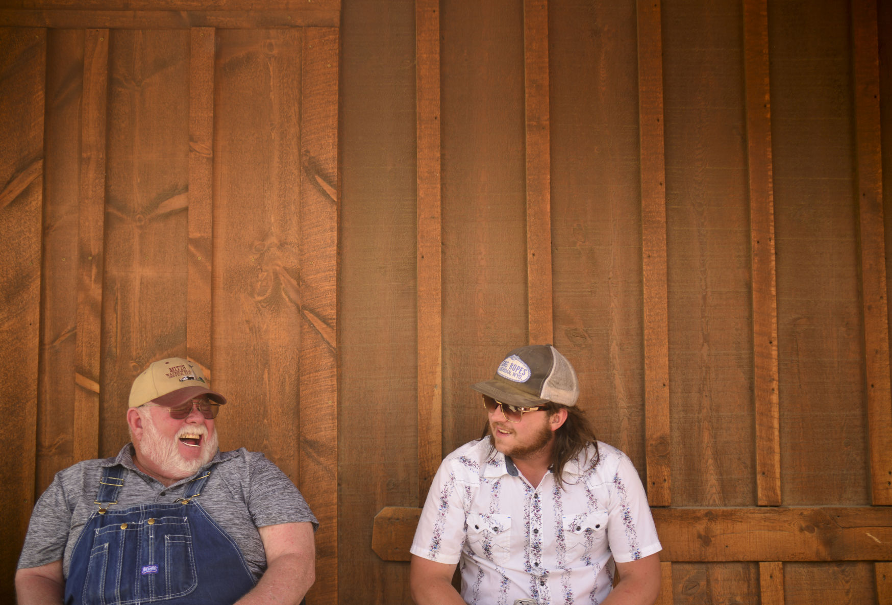 Kevin Lund and Monte Wade sit in the shade on the porch